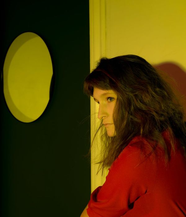Woman in a calm yoga pose in a dark room with soft yellow light.